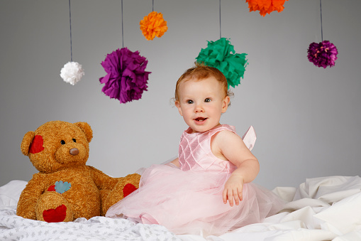 Happy Baby Portrait cute baby girl dressed in elegant evening dresses Playing with teddy bear doll
