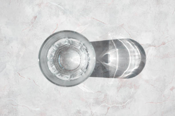 Glass of clear water on a white granite table in daylight, top view stock photo