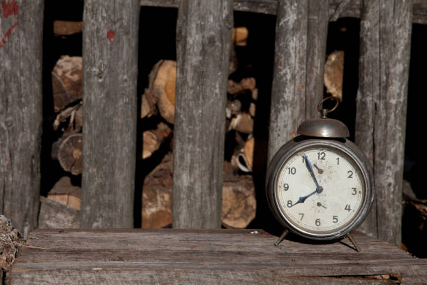 istock An old silver clock stands on a plank by a wooden fence 1171869645