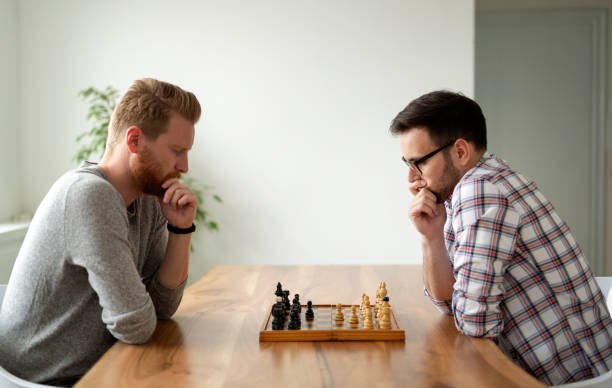 istock Young smart friends playing chess at home 1171872932