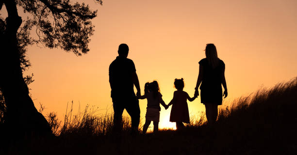istock Happy family silhouette standing on against sunset time 1171872976