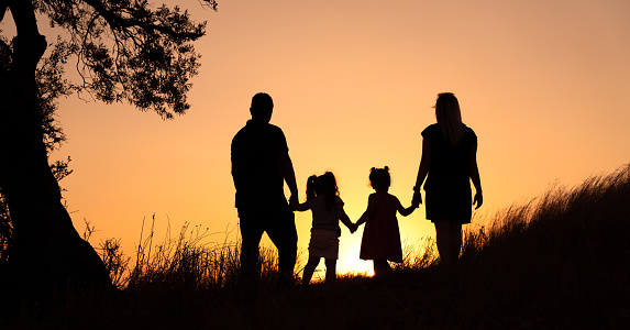 Happy family silhouette standing on against sunset time