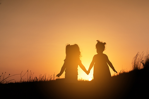 Two child standing on against sunset. Friendship concept.