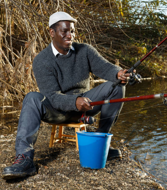 istock Positive fisherman sitting near river 1171874202