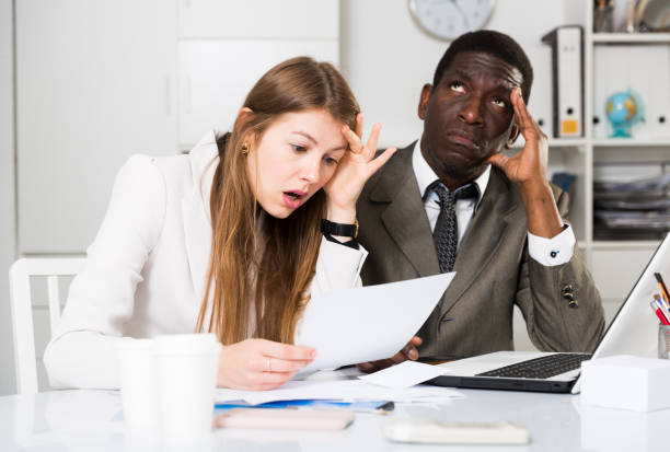 istock Unhappy managers working  with laptop and documents at table in office 1171875717