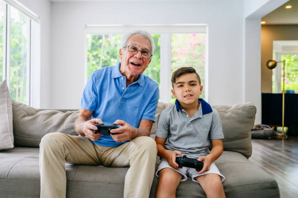 латиноамериканский дедушка играет в видеоигры с внуком - video game family child playful стоковые фото и изображения