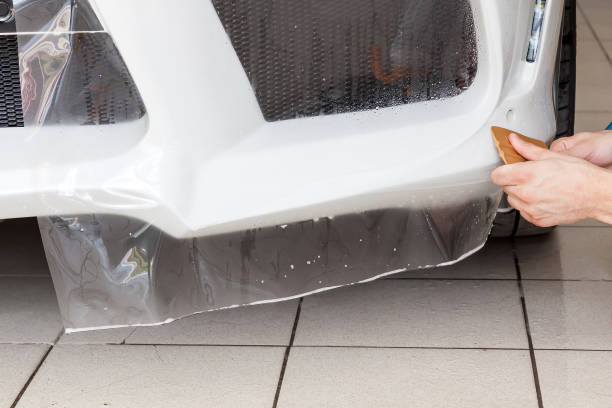 reacondicionando el coche con una sólida película protectora transparente, el maestro pega el recubrimiento protegiendo los vehículos de arañazos y virutas en el taller. - retrofitting fotografías e imágenes de stock