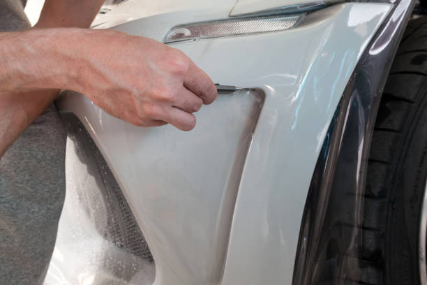 reacondicionando el coche con una sólida película protectora transparente, el maestro pega el recubrimiento protegiendo los vehículos de arañazos y virutas en el taller. - retrofitting fotografías e imágenes de stock