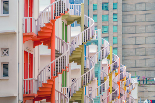Close up of colorful pastel spiral staircases in Singapore, Bugis Village, vintage style fire exit of residential buildings, apartments, or houses.
