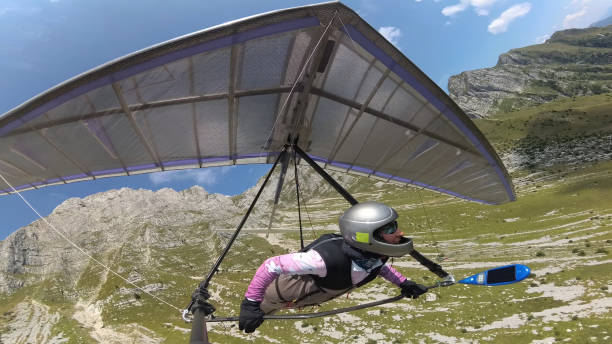 Hang glider pilot flies with his wing between high mountains.  Extreme sport in Soca valley, Slovenia Hang glider pilot flies with his wing between high mountains.  Extreme sport in Soca valley, Slovenia glider hang glider hanging sky stock pictures, royalty-free photos & images