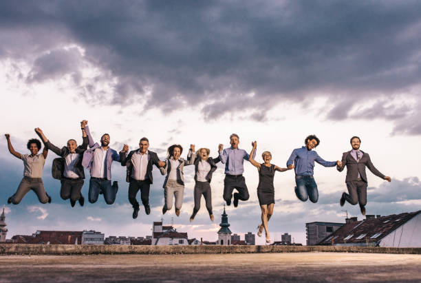 istock Cheerful business team holding hands and jumping on a rooftop. 1171889291