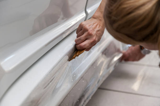 istock Retrofitting the car with a solid transparent protective film, the master glues the coating protecting the vehicles from scratches and chips in the workshop. 1171889432