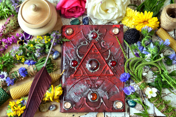 istock Decorated magic book, quill, summer herbs and flowers on witch table. 1171889661