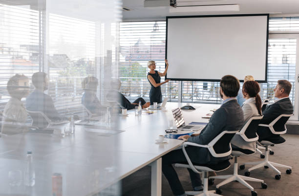 istock Mature CEO giving a business presentation through projection screen in a board room. 1171890620