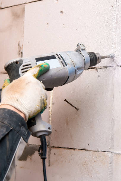 istock Hands of the Builder drilling the wall at the construction site 1171891003