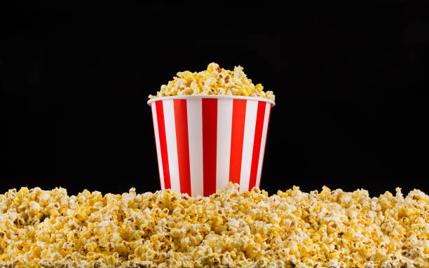 istock Paper striped bucket installed on scattered popcorn isolated on black background 1171893113
