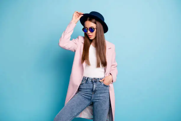 Photo of Portrait of charming stylish lady posing showing her fashionable retro outfit having free time wearing pink topcoat denim jeans isolated over blue background