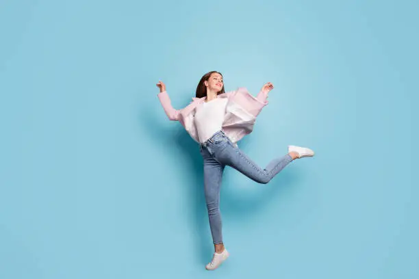 Photo of Full length photo of childish funny lovely lady jump have fun wear topcoat isolated over blue background