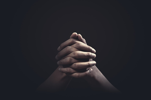 Praying hands with faith in religion and belief in God on dark background. Power of hope or love and devotion.