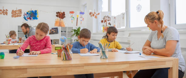 istock Female teacher supervising three children writing in their notebooks 1171896558