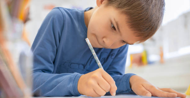 Boy writing in his notebook at school stock photo