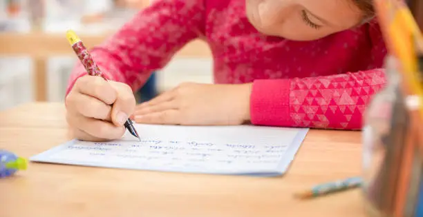 Schoolgirl writing in notebook in classroom.