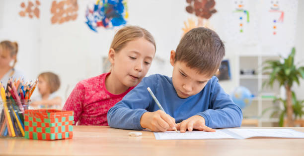 istock Girl helping boy writing something in his notebook 1171896601