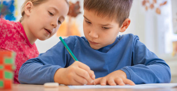 istock Girl helping boy writing something in his notebook 1171896612