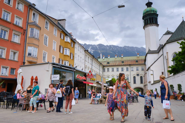 Tourists and locals stroll in the afternoon through one of the streets of the Old City of Innsbruck, very close to the Hofkirche, one of the most important monuments of the city.