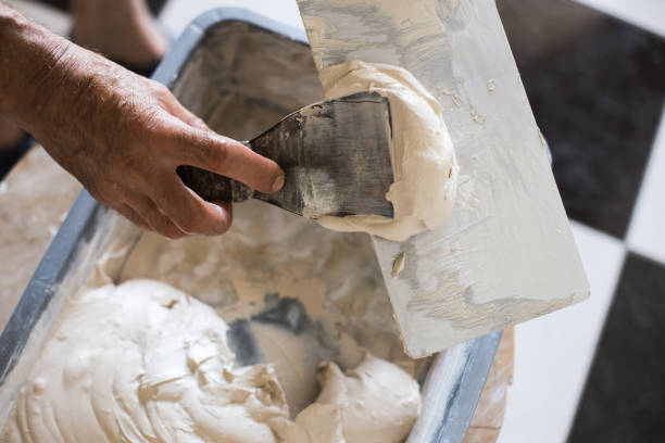 finished solution of the final putty in a plastic container, repair work Finishing works with laying ceramic tiles. bucket of putty for tile seams. Two-component decorative, acid resistant epoxy grout. hand with a plaster spatula stock pictures, royalty-free photos & images