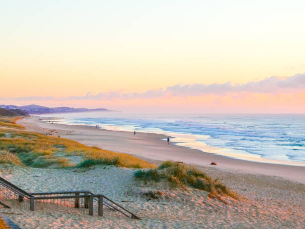 Vibrant dawn at Coolum Beach on the Sunshine Coast Pink, orange and gold sky at sunrise over the ocean, with mirror reflections on the beach mirror lake stock pictures, royalty-free photos & images