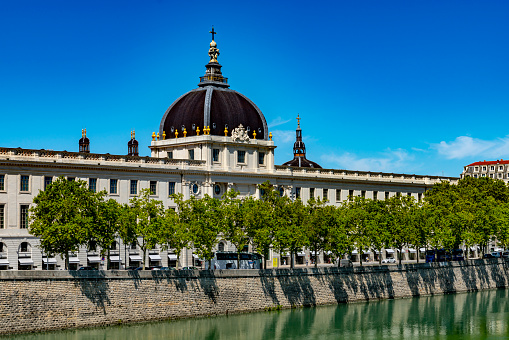 The banks of the Rhone at Lyon.  The Hotel Dieu with its reflection in the Rhone and blue skies in the background.