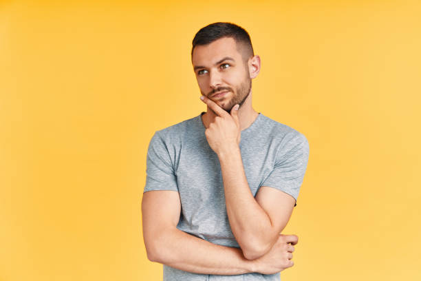 istock Young thoughtful man thinking and looking aside on copy space isolated on yellow background 1171905115