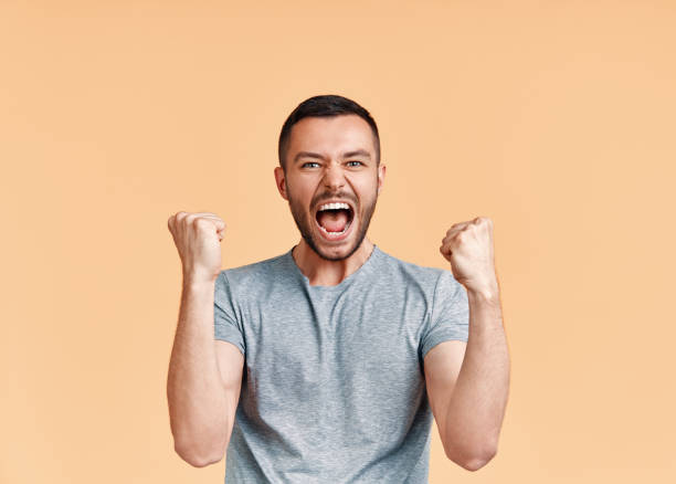 istock Happy man celebrating his success with winner gesture on beige background 1171905121