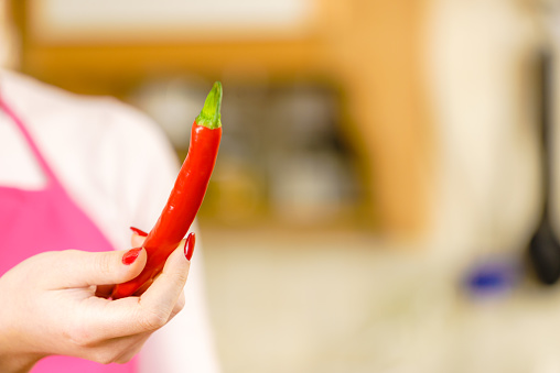 Unrecognizable woman holding red chilli hot pepper paprika. Spicy food, oriental seasonings concept.