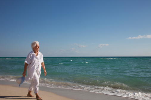 Photo of a mid adult woman walking down the beach: taking care of herself, her mental and physical health