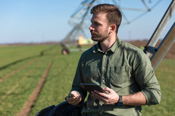 istock Young farmer standing in wheat field and setup irrigation system on tablet. 1171910136
