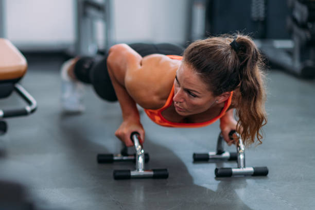 athlète féminin faisant des pompes dans le gymnastique - athlete push ups muscular build female photos et images de collection