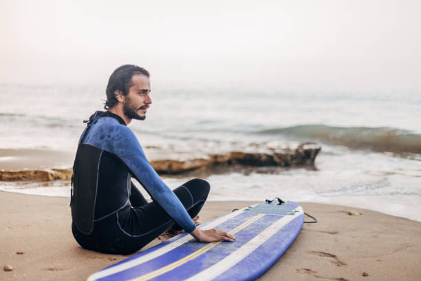 istock Young  surfer sitting on the beach 1171913596