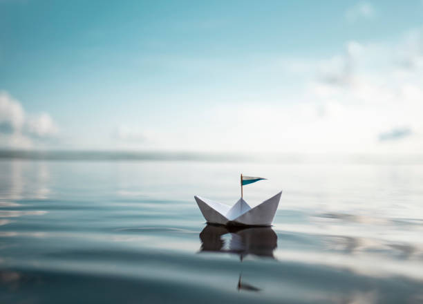 小さな紙ボートが穏やかな水に浮かぶ - 静水 ストックフォトと画像