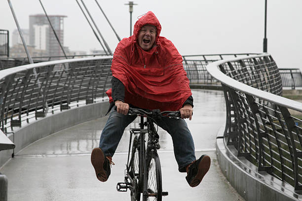 uomo in pioggia sulla bici divertendosi - london in the rain foto e immagini stock