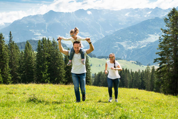 rodzina z córką biegającą po polu w górach - mountain freedom european alps austria zdjęcia i obrazy z banku zdjęć