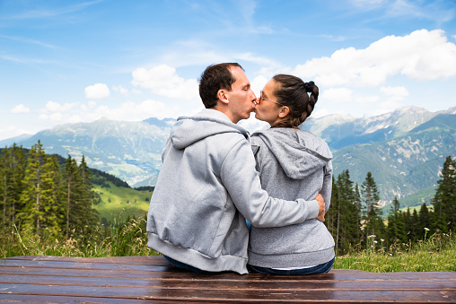Couple Sitting On Bench Enjoying Panoramic Mountain View