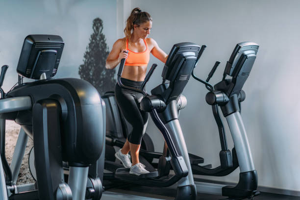 woman exercising on elliptical cross trainer - oval shape fotos imagens e fotografias de stock