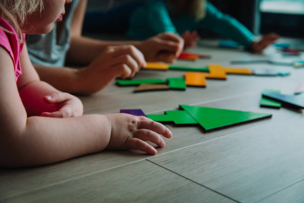 istock teacher and kids play with puzzle, doing tangram 1171915540