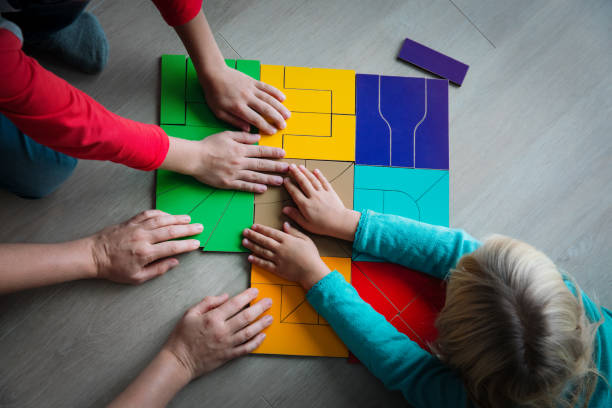 istock teacher and kids play with puzzle, doing tangram 1171915558