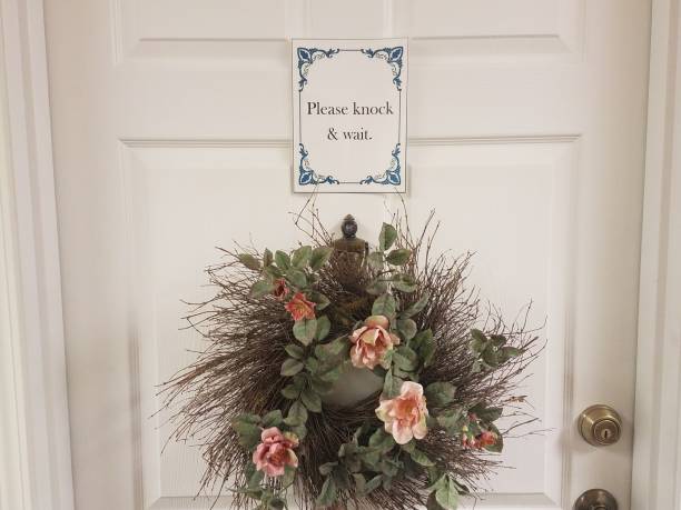 istock please knock and wait sign on white door with wreath 1171917045