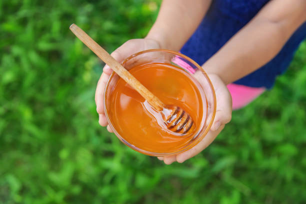 Child a plate of honey in the hands. Selective focus.