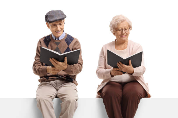 homem idoso e mulher assentados em livros de leitura do painel - men reading outdoors book - fotografias e filmes do acervo