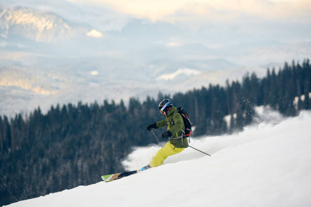 skifahrer steigen vom schneebedeckten hochgebirgsgipfel ab. extremes back-country-ski-konzept. blick auf die berge im hintergrund - back country skiing extreme skiing skiing ski stock-fotos und bilder